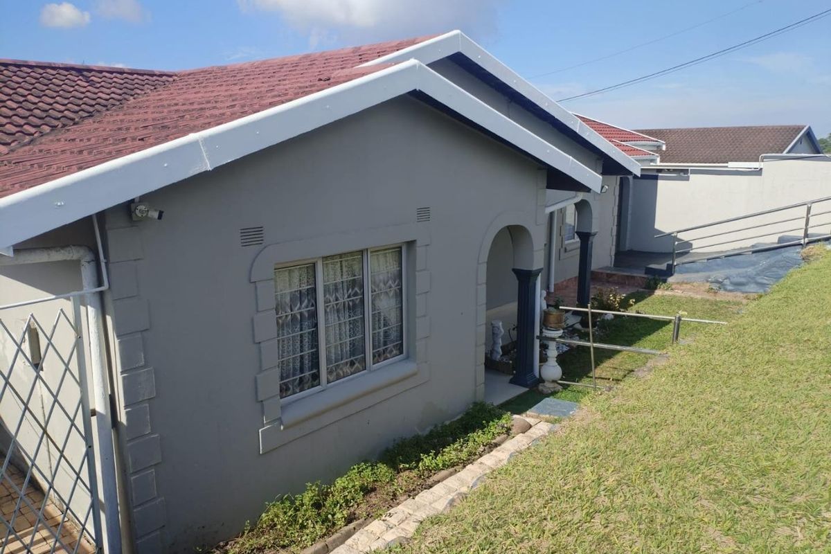 A view of the rear exterior of the house featuring a tiled roof, grey painted walls, and a covered entrance area.