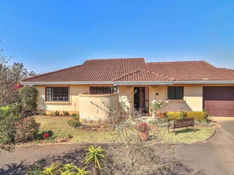 Front elevation of a townhouse featuring a tiled roof, a single garage, and a paved driveway with a landscaped front garden.