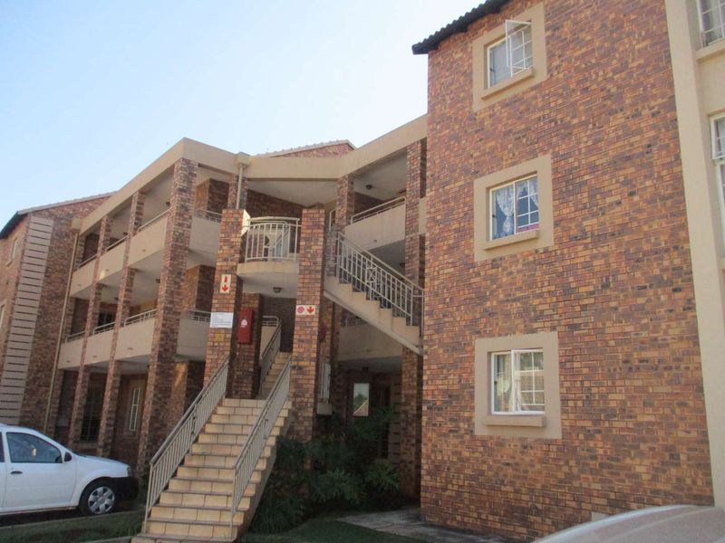 Exterior view of a multi-story apartment complex featuring face brick construction, external staircases with metal railings, and multiple residential units.