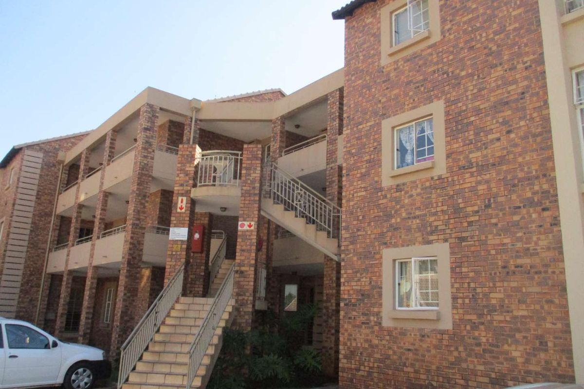 Exterior view of a multi-story apartment complex featuring face brick construction, external staircases with metal railings, and multiple residential units.