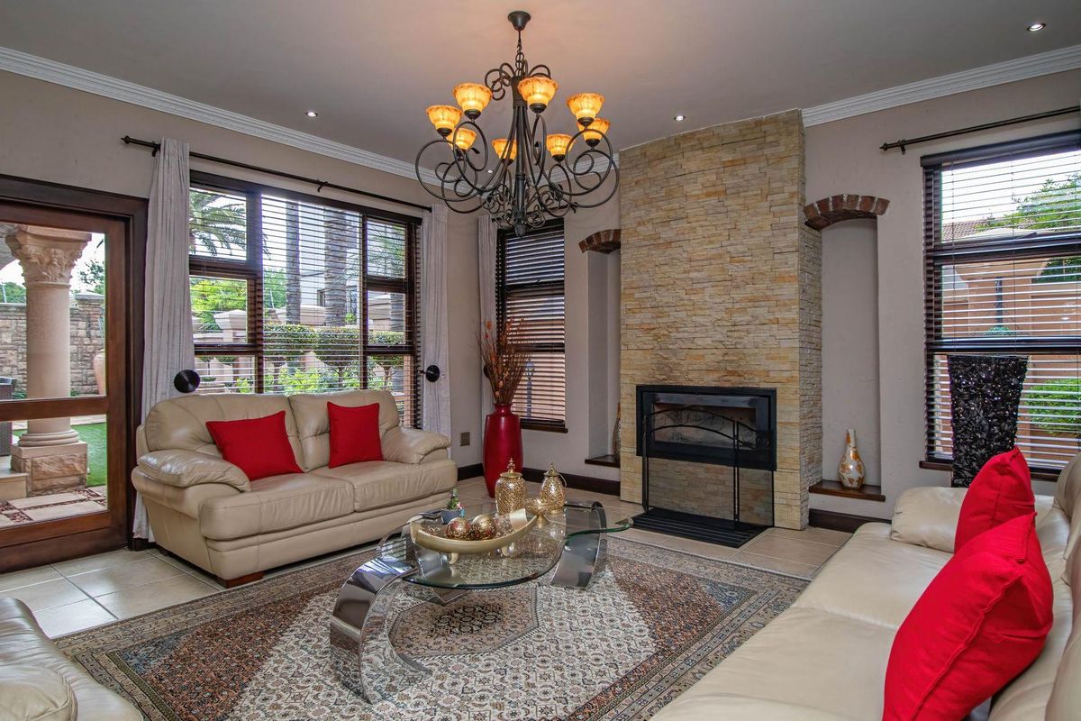 Spacious living room featuring a prominent stone-clad fireplace, large windows with blinds, recessed lighting, and a decorative chandelier.