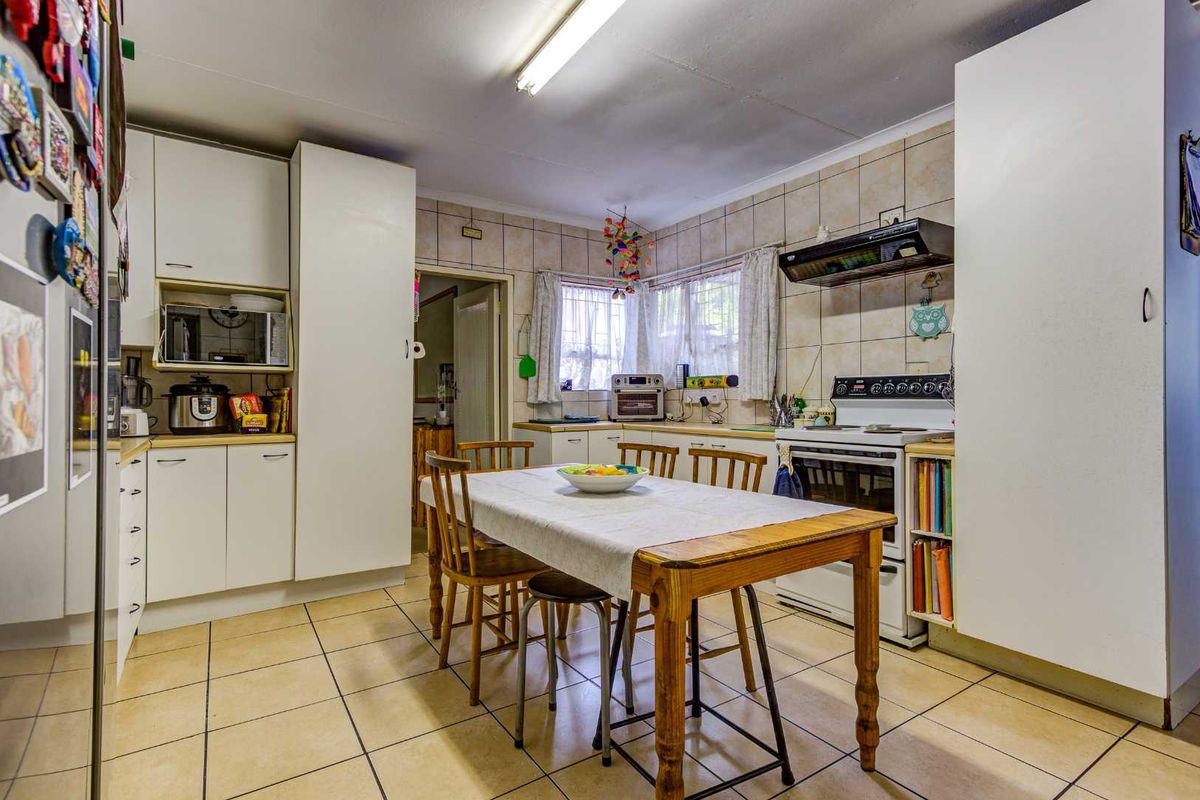 A functional kitchen featuring white cabinetry, tiled splashbacks, tiled flooring, and a built-in stove with an extractor fan, offering a practical layout.