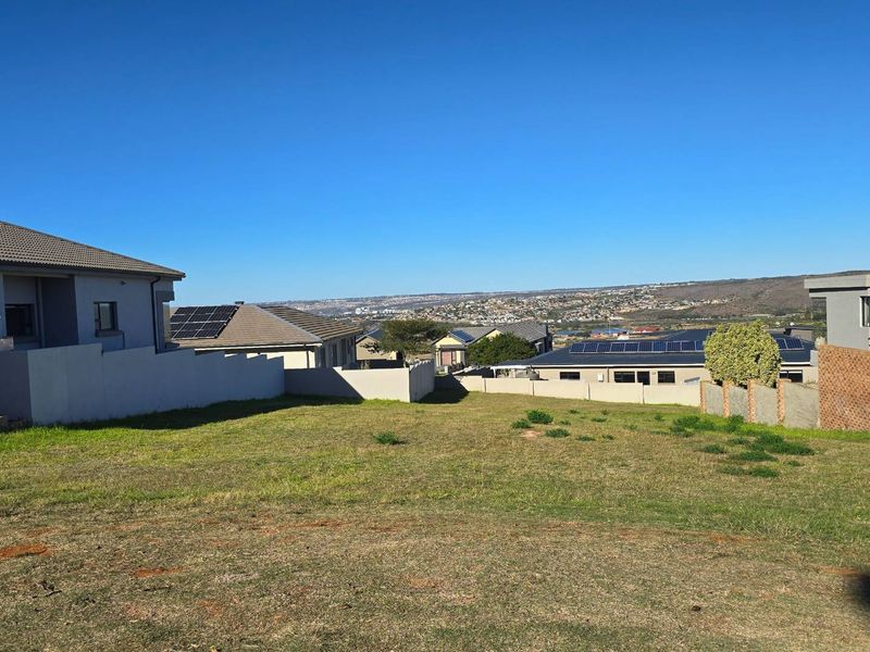 A vacant residential plot situated in a developed neighborhood, featuring established boundary walls and scenic views of the surrounding area.