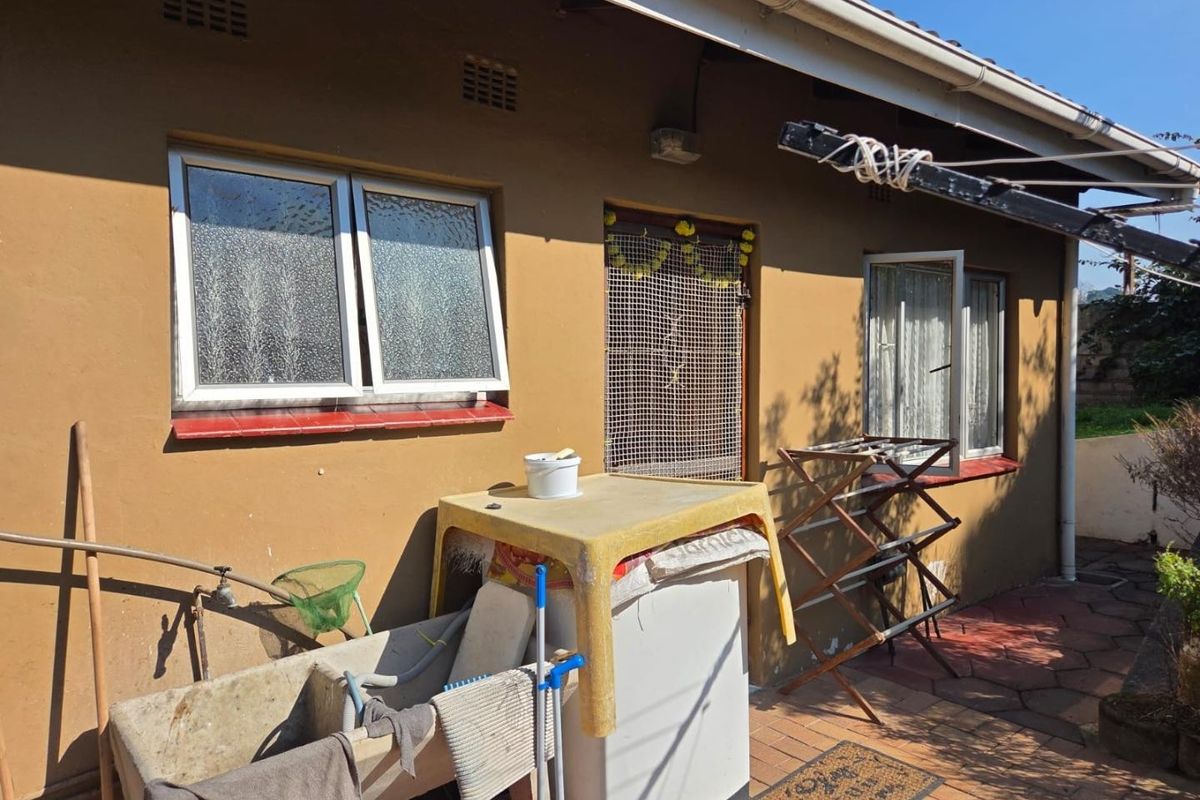 Rear exterior view of the property featuring a paved patio area, concrete laundry trough, and aluminium window frames.