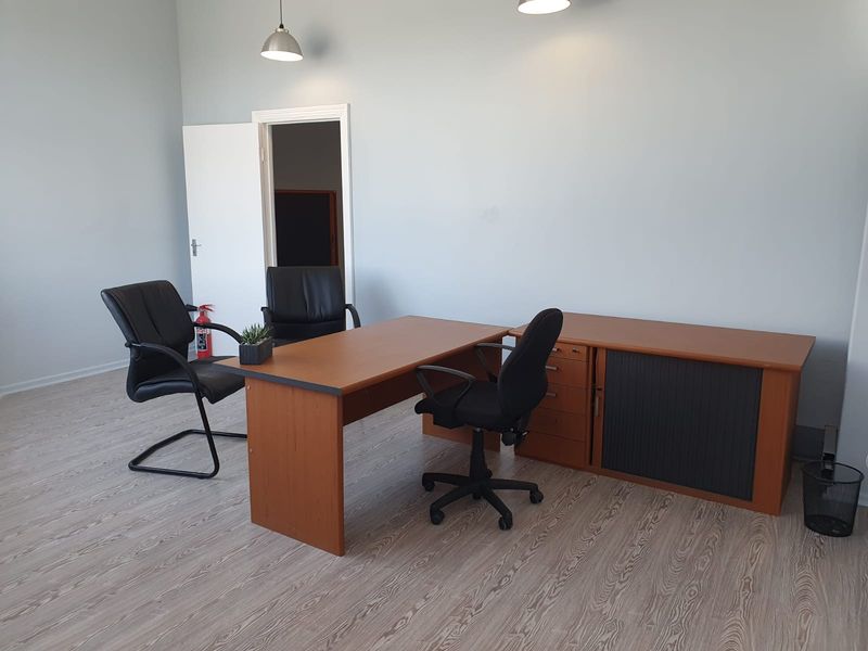 A functional office space featuring light-toned laminate flooring and modern pendant lighting, providing a clean and professional environment.