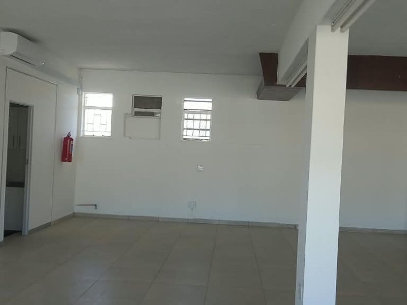 A spacious, open-plan retail area featuring tiled flooring, a support column, and wall-mounted air conditioning, offering a versatile layout for various business needs.
