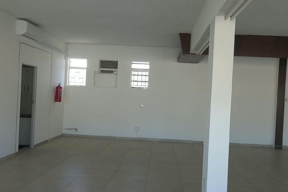A spacious, open-plan retail area featuring tiled flooring, a support column, and wall-mounted air conditioning, offering a versatile layout for various business needs.
