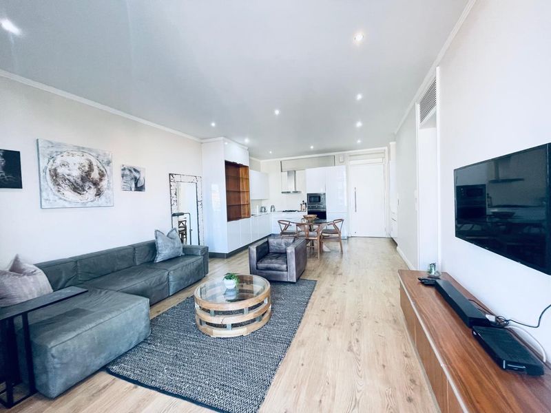 Spacious open-plan living area featuring modern laminate flooring, recessed lighting, and a sleek, well-appointed kitchen with integrated appliances.