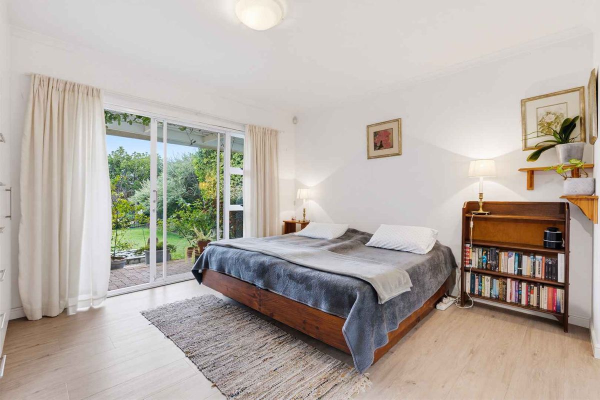 Bright bedroom featuring light laminate flooring and large sliding glass doors providing direct access to the rear garden.