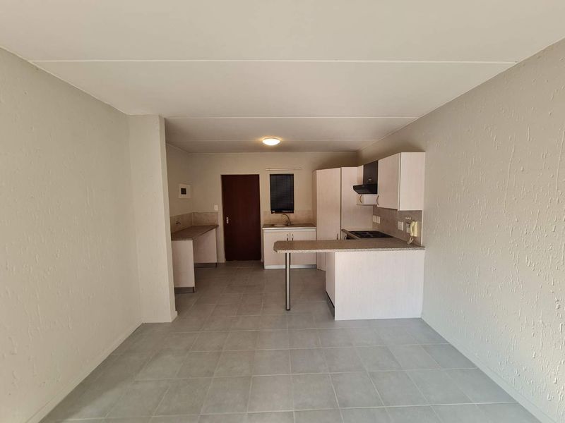 A functional, empty kitchen featuring built-in cabinetry, laminate countertops, a breakfast bar, and tiled flooring, offering a clean canvas for potential updates.