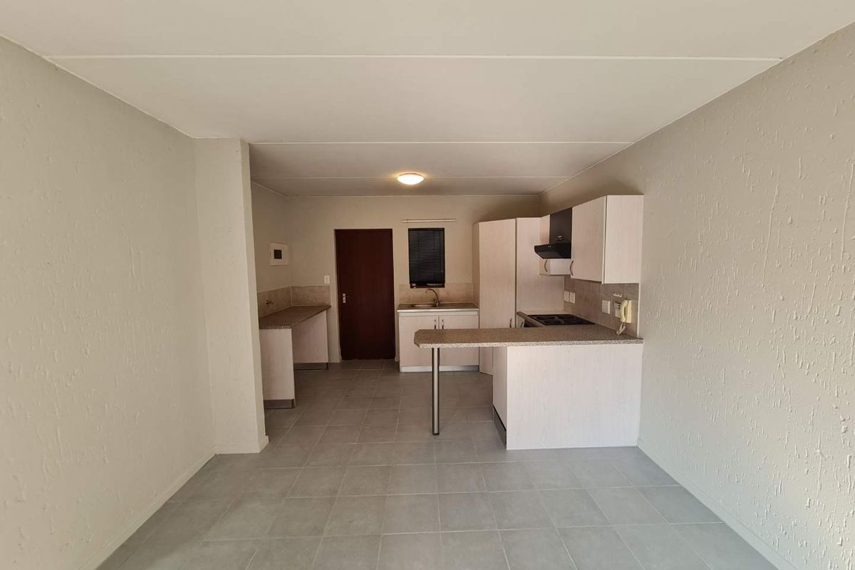 A functional, empty kitchen featuring built-in cabinetry, laminate countertops, a breakfast bar, and tiled flooring, offering a clean canvas for potential updates.