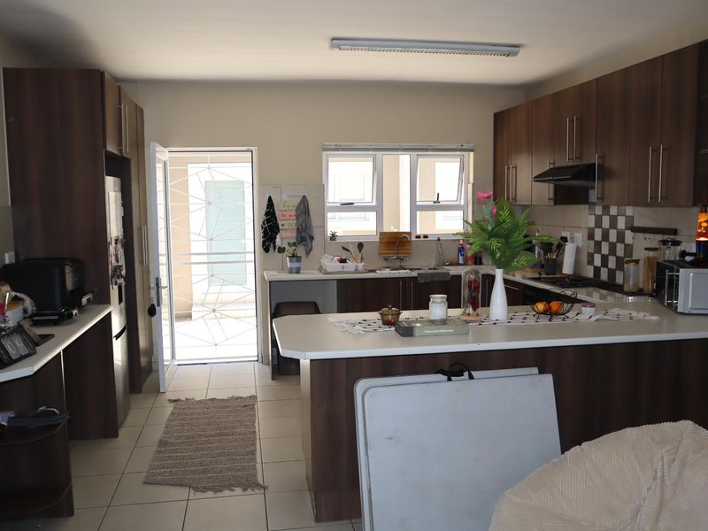 Functional kitchen featuring dark wood cabinetry, tiled backsplash, ample counter space, and direct access to an exterior security gate.