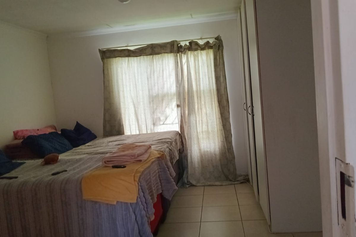 A bedroom featuring built-in cupboards and tiled flooring, offering a functional space with potential for cosmetic updates.