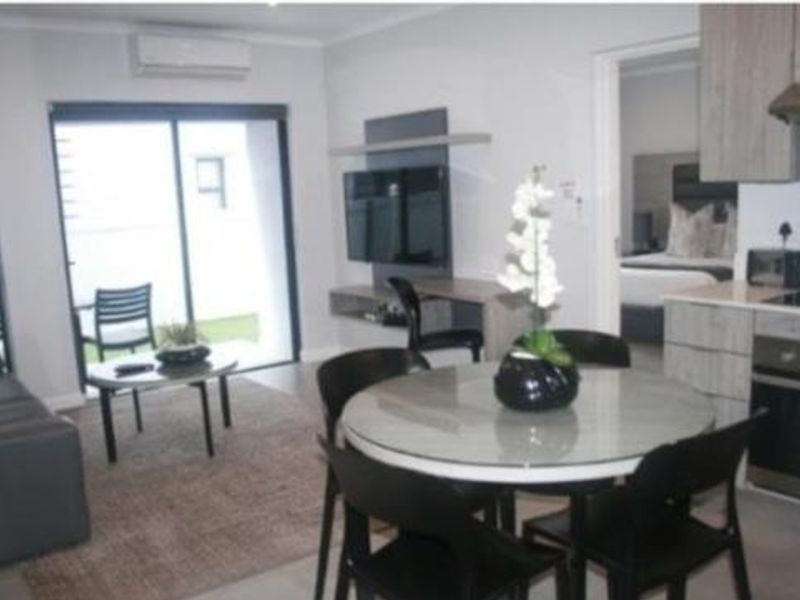 Open-plan living and dining area featuring a modern kitchen with built-in appliances, air conditioning, and direct access to an outdoor patio space.