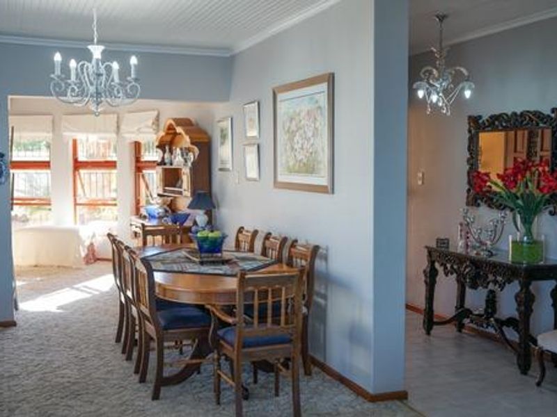 A well-lit dining room featuring a beadboard ceiling, elegant chandelier, and large windows that provide ample natural light to the space.