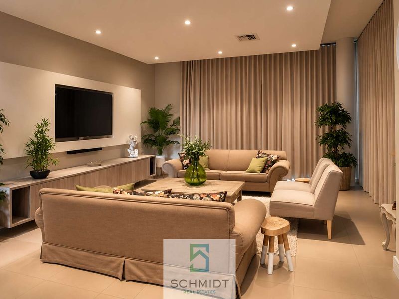 A modern, well-appointed living room featuring a built-in media console, integrated fireplace, recessed lighting, and neutral tiled flooring with elegant floor-to-ceiling drapery.