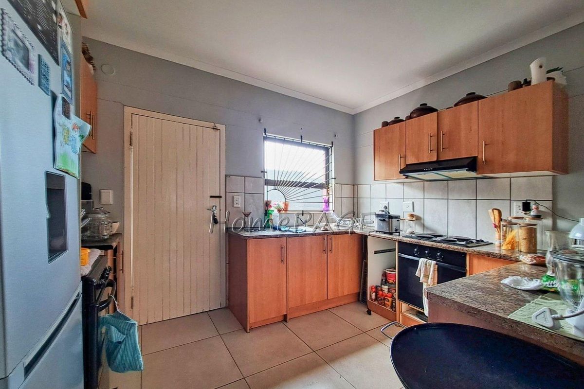 A functional kitchen featuring wood-finish cabinetry, tiled flooring, a built-in oven with extractor fan, and a tiled backsplash.