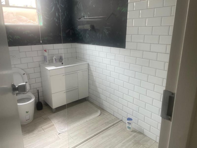 Modern bathroom featuring white subway wall tiles, a contemporary vanity cabinet, and a glass shower screen.