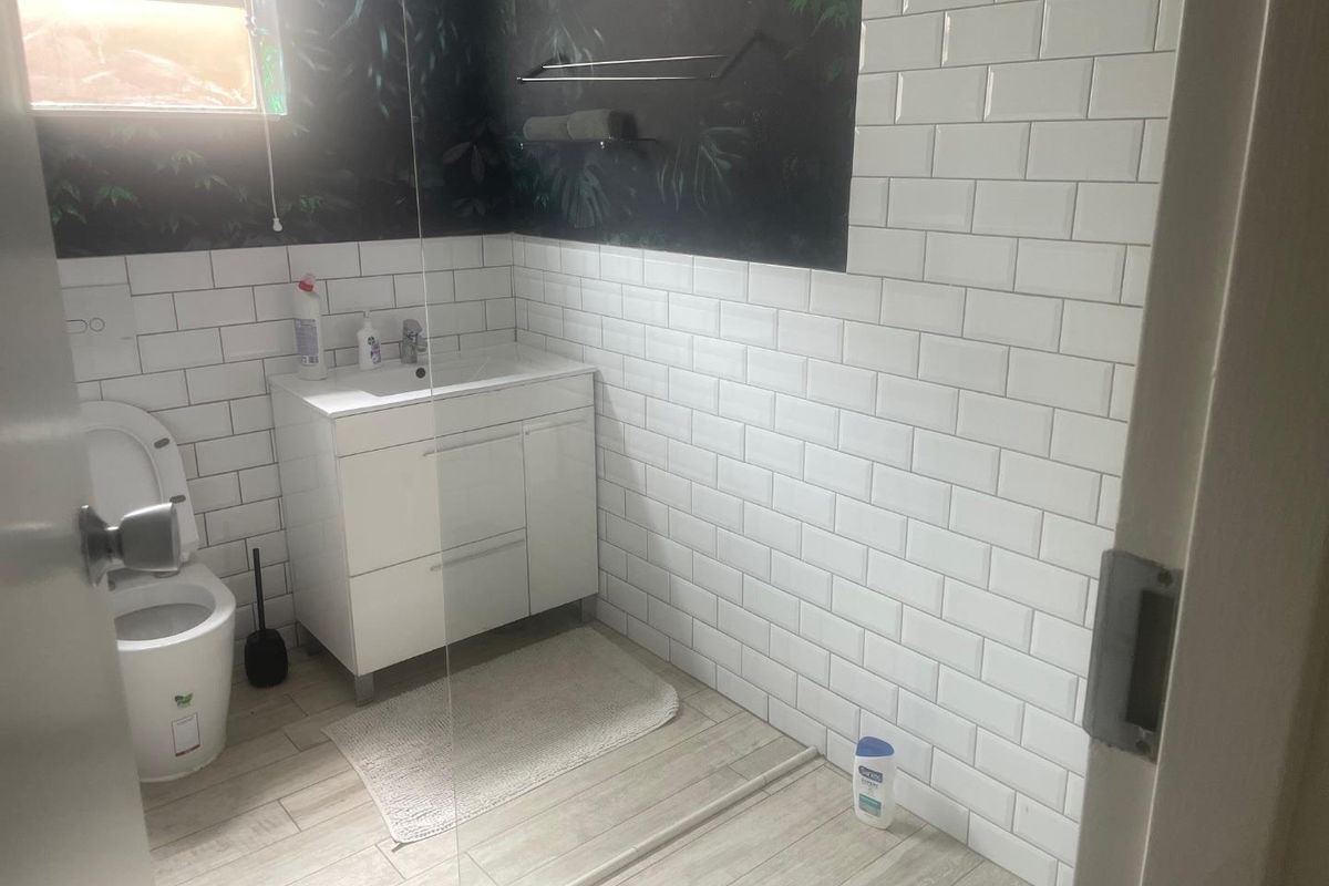Modern bathroom featuring white subway wall tiles, a contemporary vanity cabinet, and a glass shower screen.