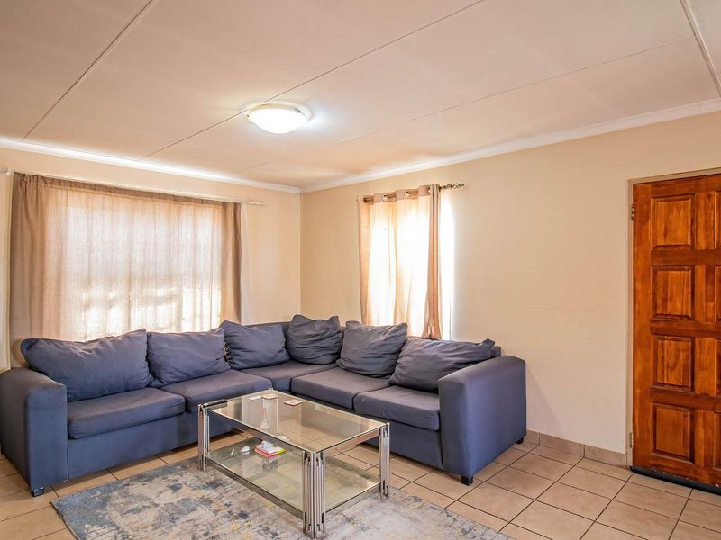 A functional living room featuring tiled flooring, a wooden panel door, and neutral wall finishes, providing a comfortable and practical living space.