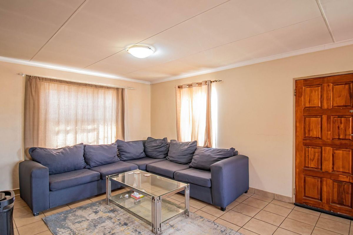 A functional living room featuring tiled flooring, a wooden panel door, and neutral wall finishes, providing a comfortable and practical living space.