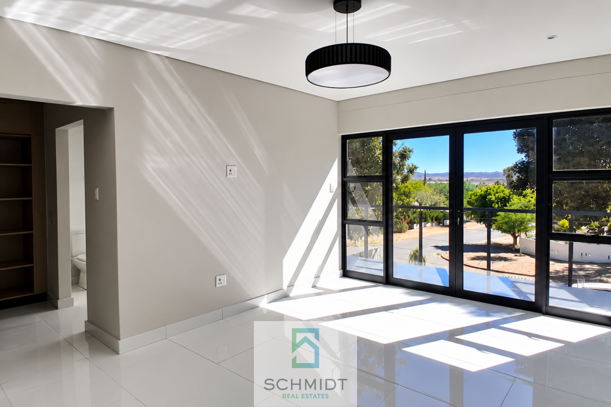 Bright and modern bedroom featuring polished tile floors, built-in shelving, and large glass sliding doors opening onto a balcony with scenic views.