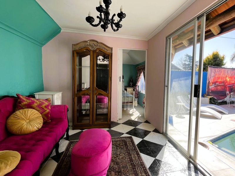 A living room featuring black and white checkered tile flooring and large sliding glass doors providing direct access to the pool area.