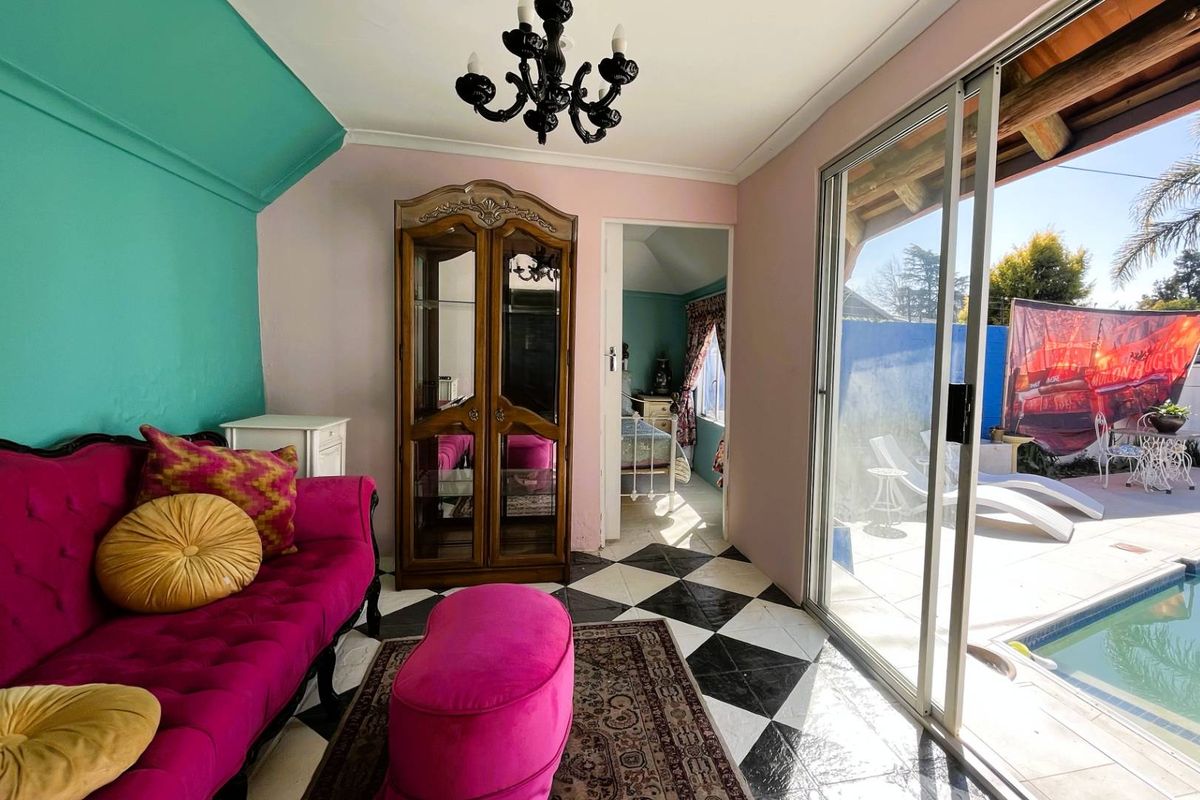 A living room featuring black and white checkered tile flooring and large sliding glass doors providing direct access to the pool area.