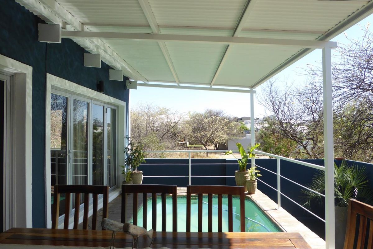 A covered patio area featuring a built-in swimming pool, metal railing, and direct access to the interior through sliding glass doors.