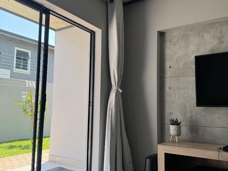Modern living room featuring a concrete accent wall, laminate flooring, and large sliding glass doors providing access to the outdoor patio area.