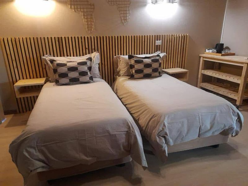 A well-maintained bedroom featuring a custom slatted timber headboard with integrated wall-mounted bedside shelves and warm wall sconce lighting.