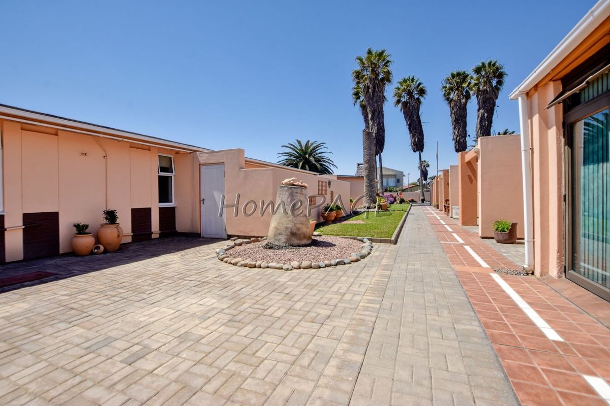 A well-maintained paved courtyard area featuring brick walling, a landscaped garden strip, and access to the residence via a sliding glass door.