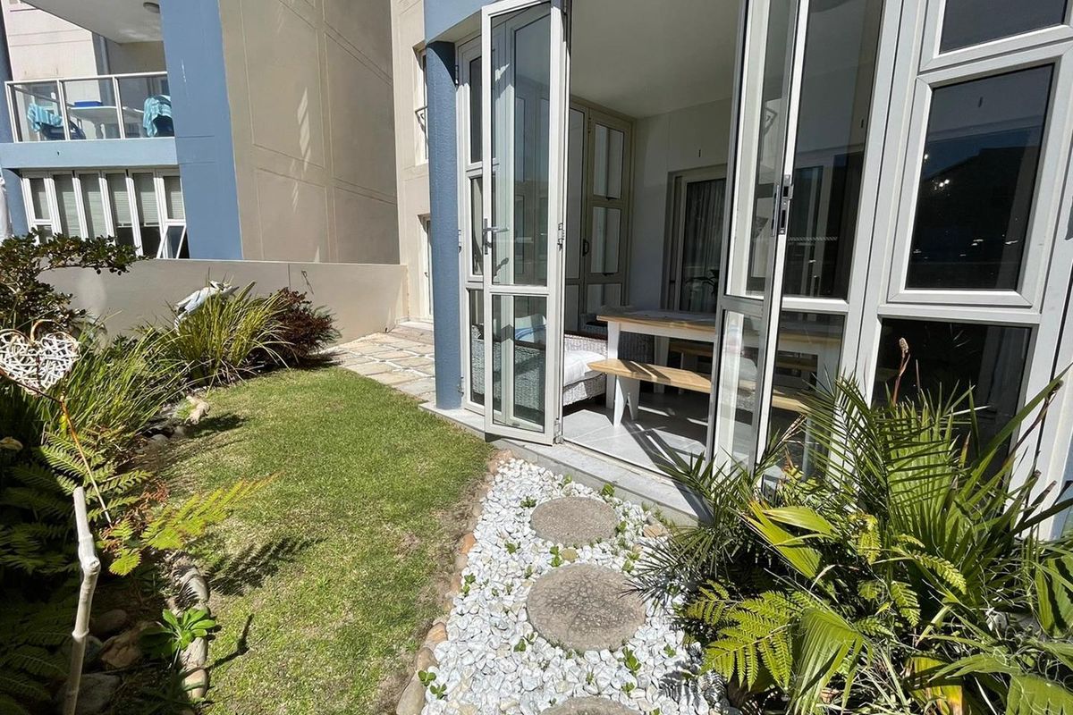 A private rear garden area featuring a stone pathway and double glass doors providing seamless access to the interior living space.