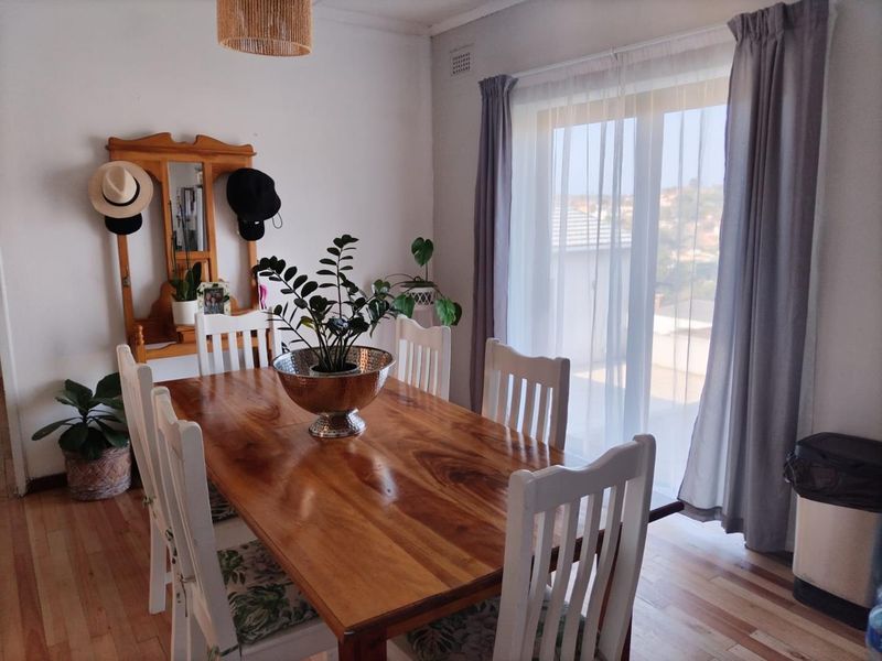 A dining room featuring laminate flooring and a sliding glass door that provides natural light and access to the exterior.