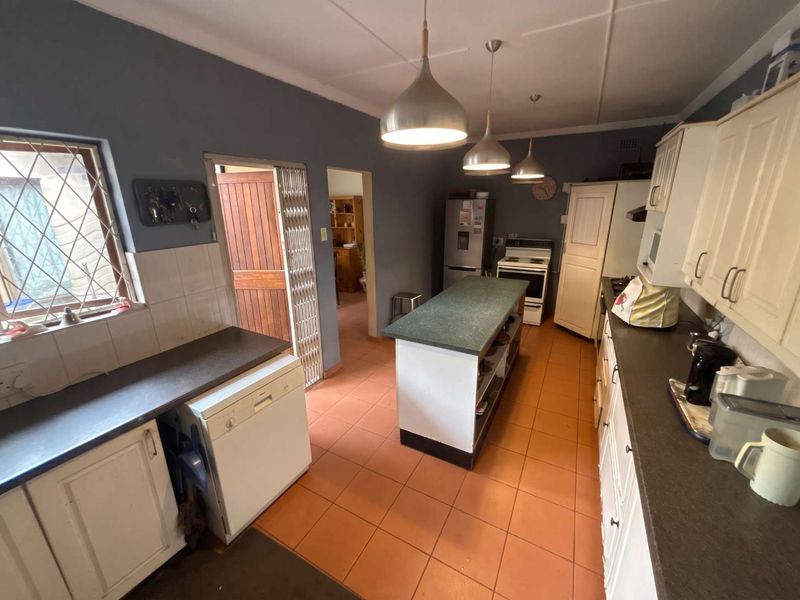 A functional kitchen featuring a central island, ample cabinetry, and tiled flooring, offering a practical layout with direct access to adjacent living areas.
