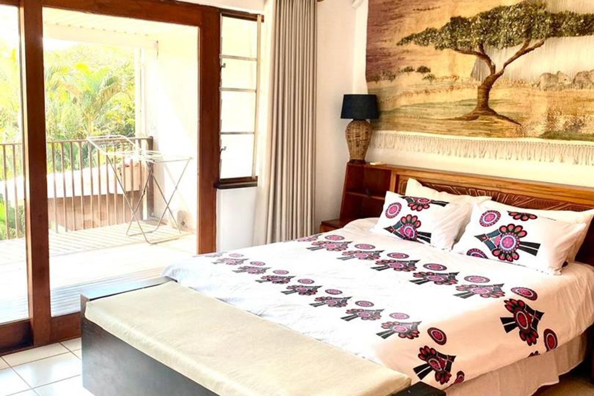 A bedroom featuring tiled flooring, a ceiling fan, and a sliding glass door providing access to an outdoor balcony area.