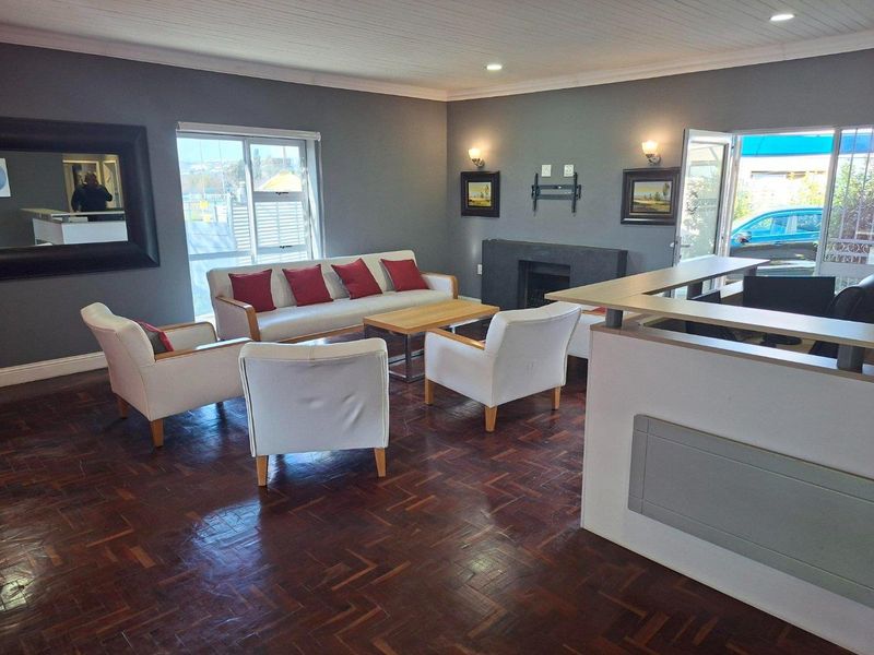 Spacious living area featuring dark parquet flooring, a built-in fireplace, and a reception counter, with natural light from sliding glass doors.