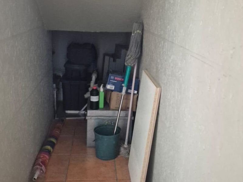 A narrow utility or storage space featuring tiled flooring, suitable for general household storage or as a small service area.