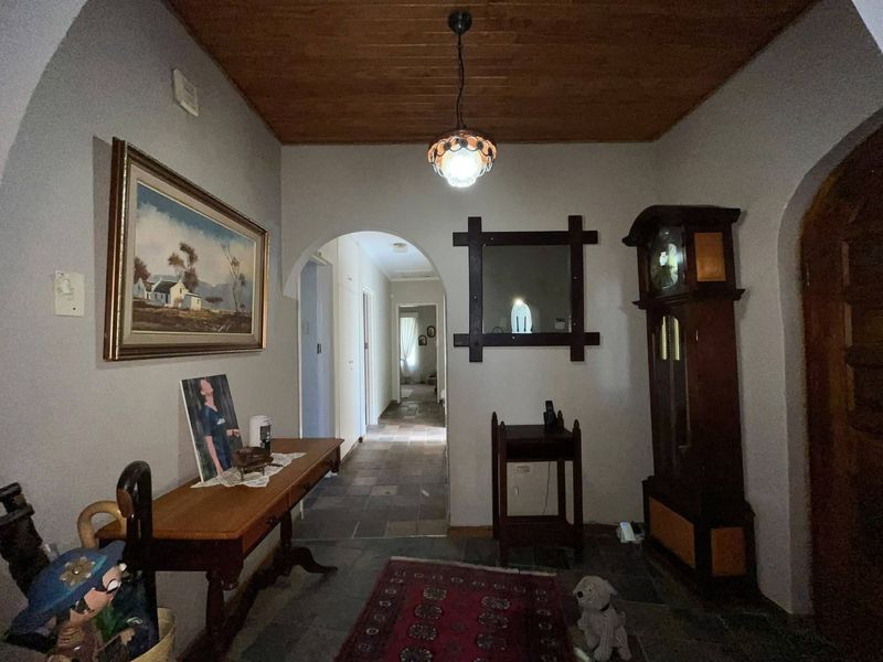 Welcoming entrance hall featuring a timber-clad ceiling, stone floor tiles, and an arched transition leading into the home's interior hallway.