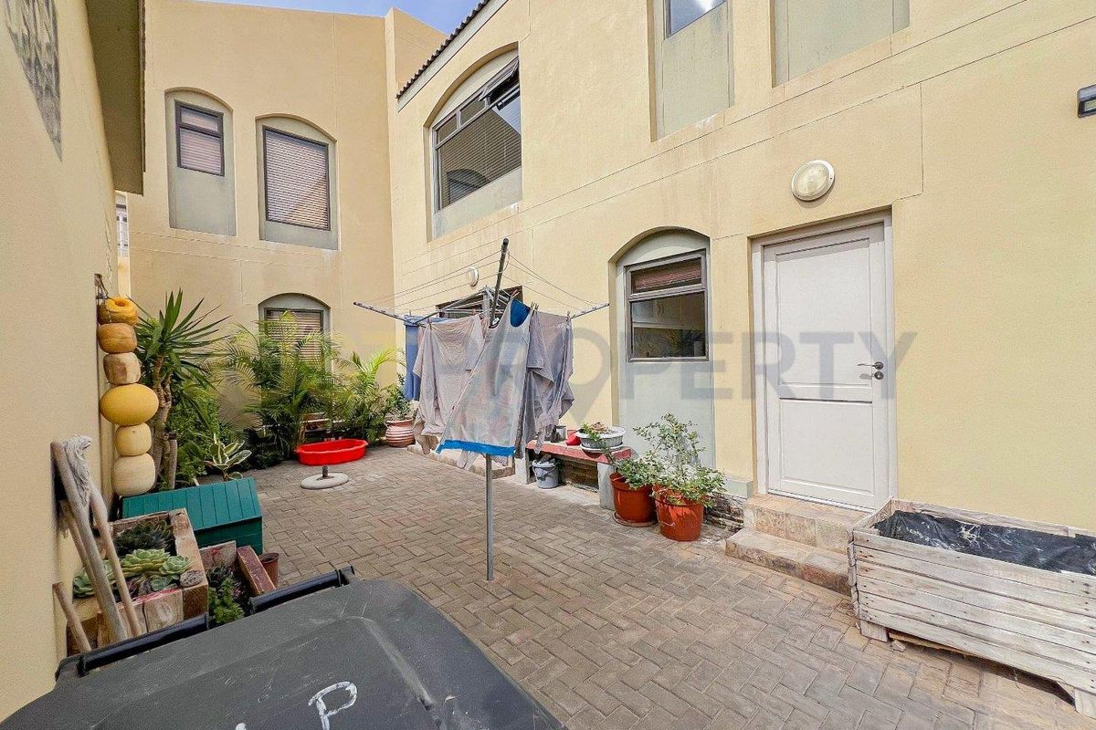 A paved rear courtyard area featuring exterior wall access, suitable for outdoor utility use or small garden space.