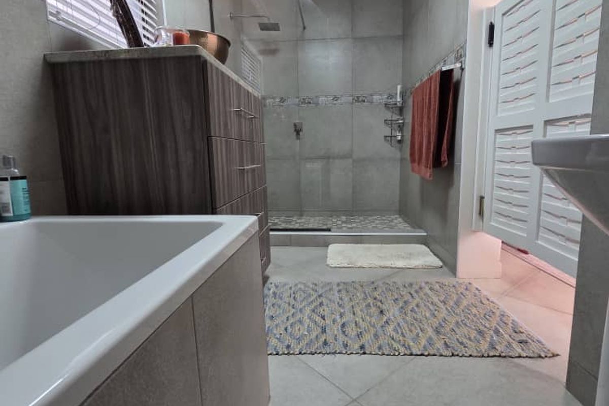 Modern bathroom featuring a walk-in shower with glass screen, tiled flooring, vanity cabinet, and a bathtub.