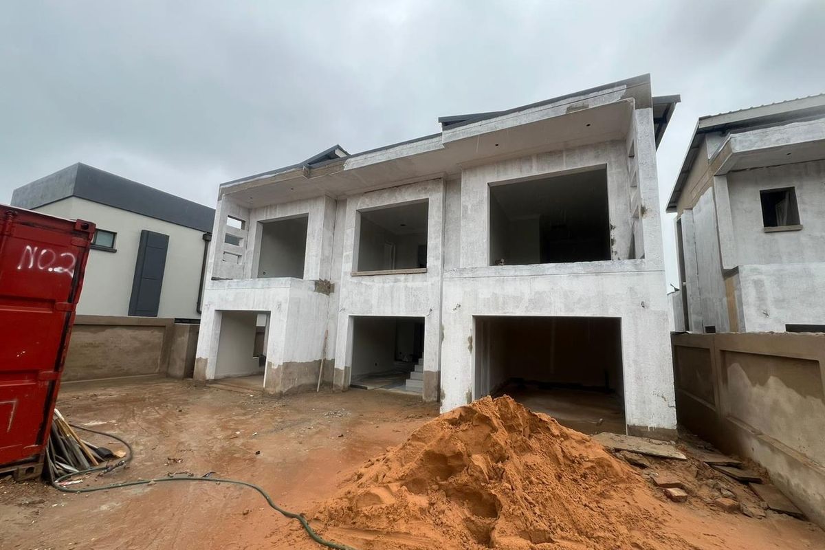 A two-story residential property currently under construction, featuring an open-plan structural shell with exposed concrete and an unlandscaped site.