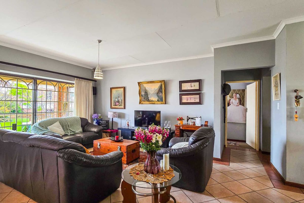 A spacious living room featuring tiled flooring, coved ceilings, and a large sliding glass door providing access to the outdoor area.