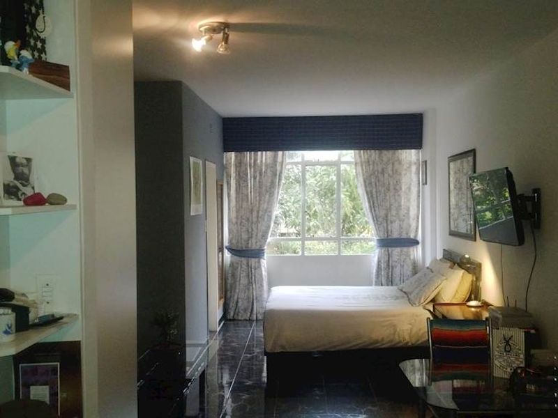 A bedroom featuring tiled flooring, built-in shelving, and a window with natural light, providing a functional living space.