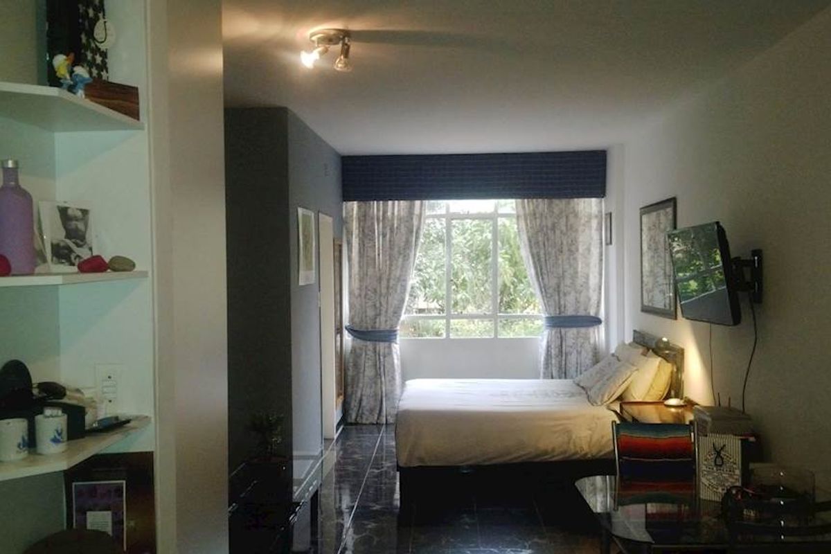 A bedroom featuring tiled flooring, built-in shelving, and a window with natural light, providing a functional living space.