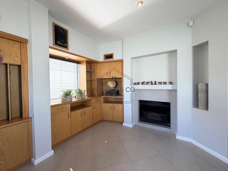 A living room featuring built-in wooden cabinetry, a fireplace, and tiled flooring, offering a functional and well-maintained space.
