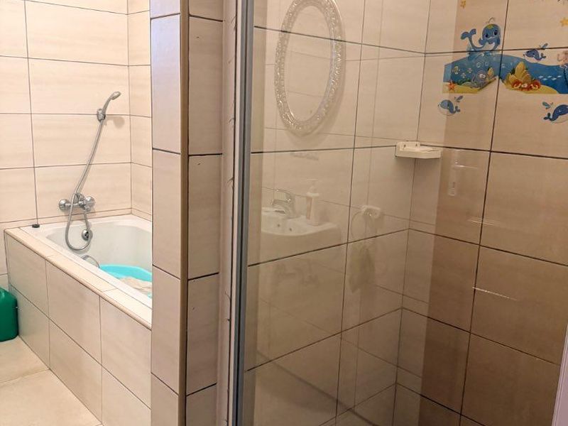 A functional bathroom featuring a separate bathtub and a glass-enclosed shower with tiled walls and flooring.