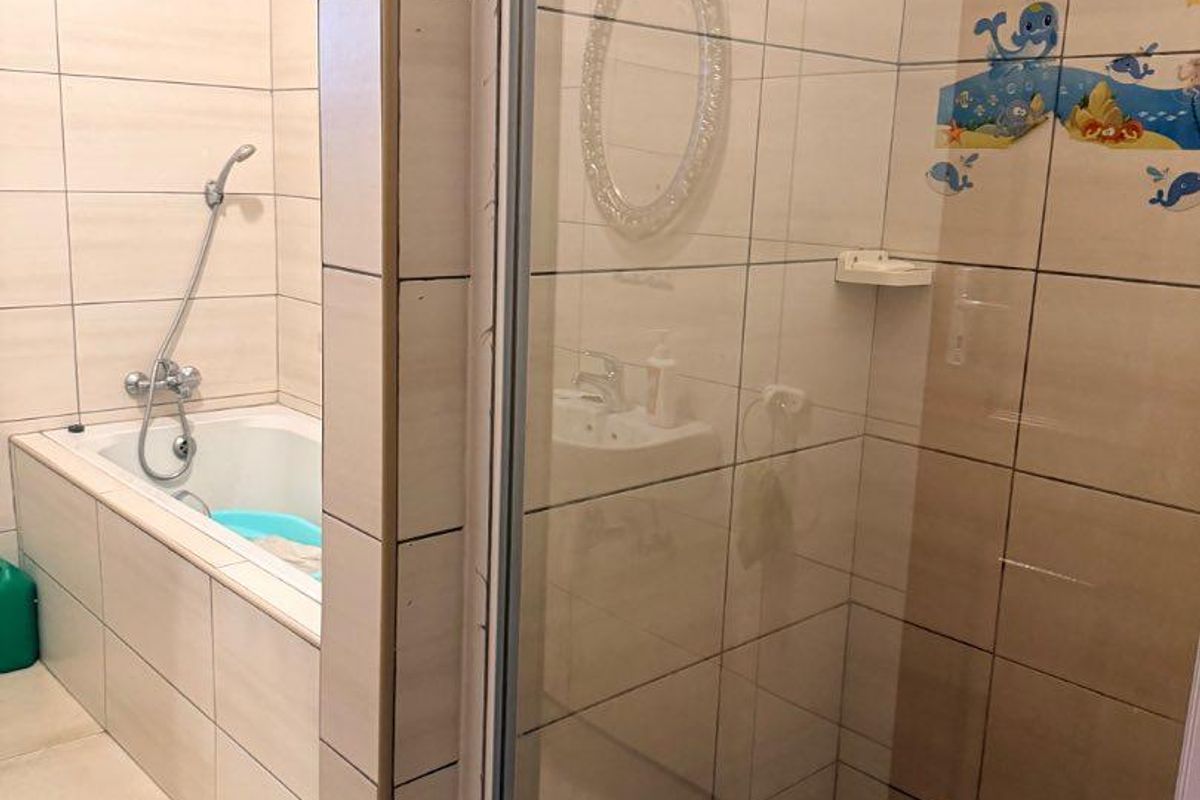 A functional bathroom featuring a separate bathtub and a glass-enclosed shower with tiled walls and flooring.