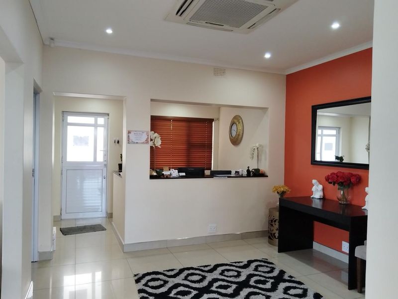 A professional office reception area featuring a built-in service counter, recessed lighting, and tiled flooring with a bright accent wall.