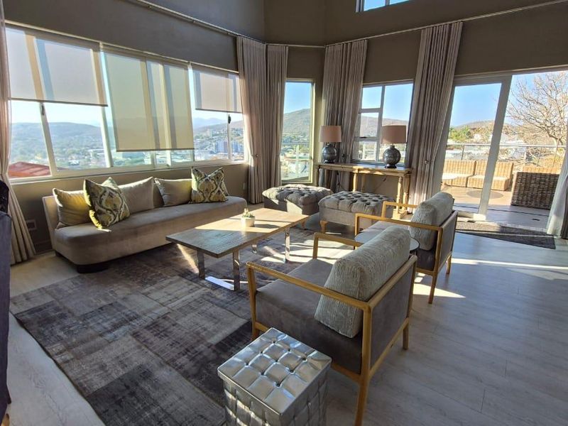 Spacious living room featuring high ceilings, large windows with panoramic views, and direct access to an outdoor patio area.